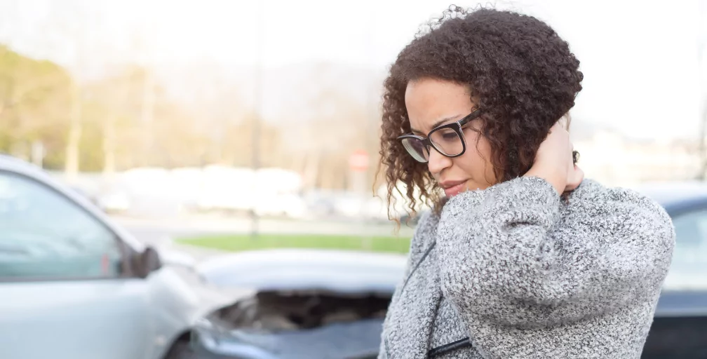 A woman stands at the scene of a wreck, looks down and puts her hand behind her neck. Silver & Archibald can help you find a respected Georgia personal injury lawyer.