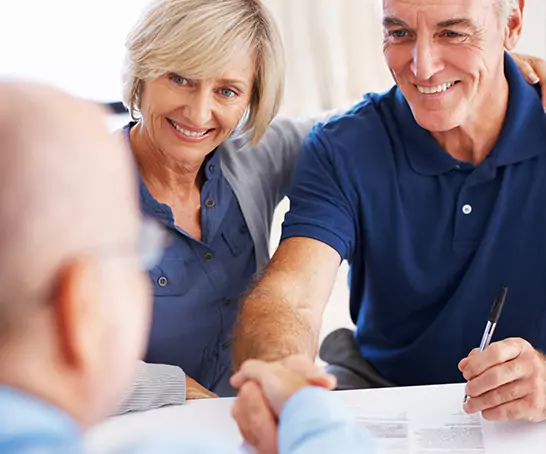 A couple sits across a table from a man in business attire, smiling and shaking hands. The Georgia disability lawyers at Silver & Archibald help with multiple types of injury and disability claims.