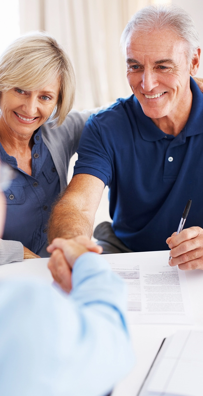 A couple sits across a table from a man in business attire, smiling and shaking hands. The Georgia disability lawyers at Silver & Archibald help with multiple types of injury and disability claims.