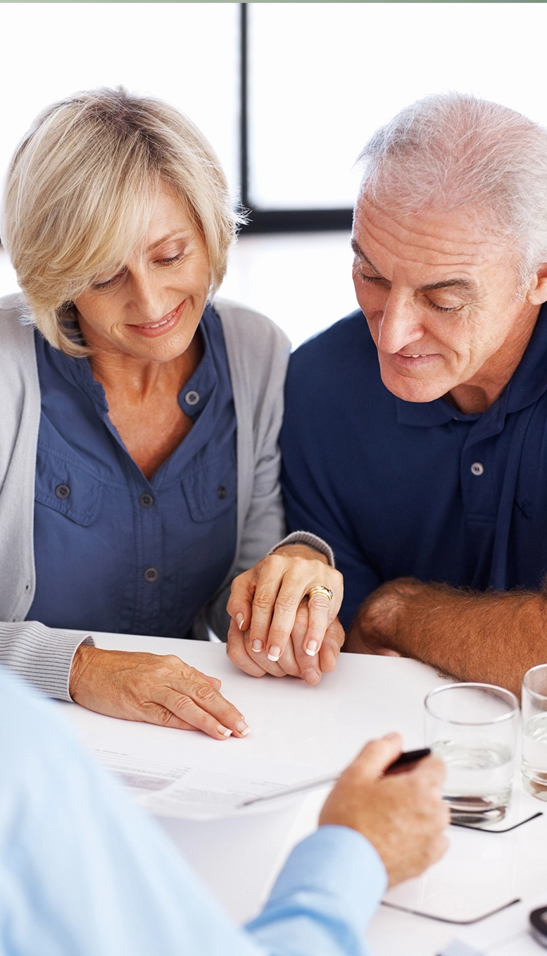 A woman and man sit at a table reviewing paperwork, her hand on his. The Georgia Social Security lawyers at Silver & Archibald are both highly skilled and deeply caring as they help you get Social Security Disability benefits